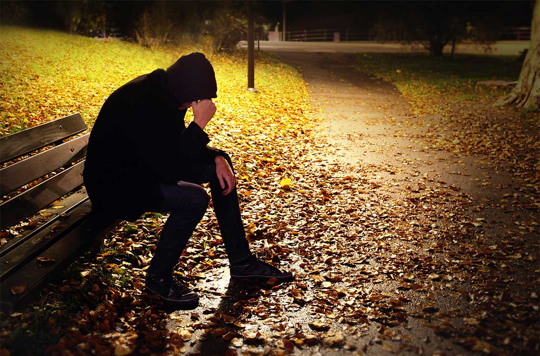 Man sitting on bench with his head down