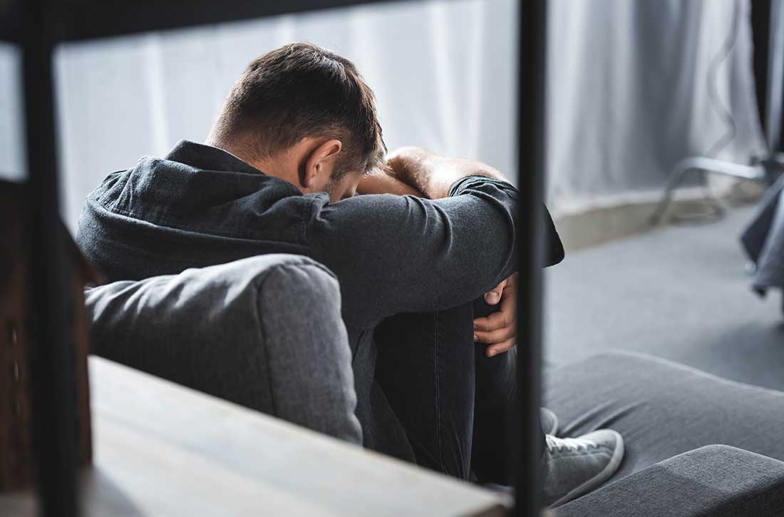 Man sitting on ground with head down