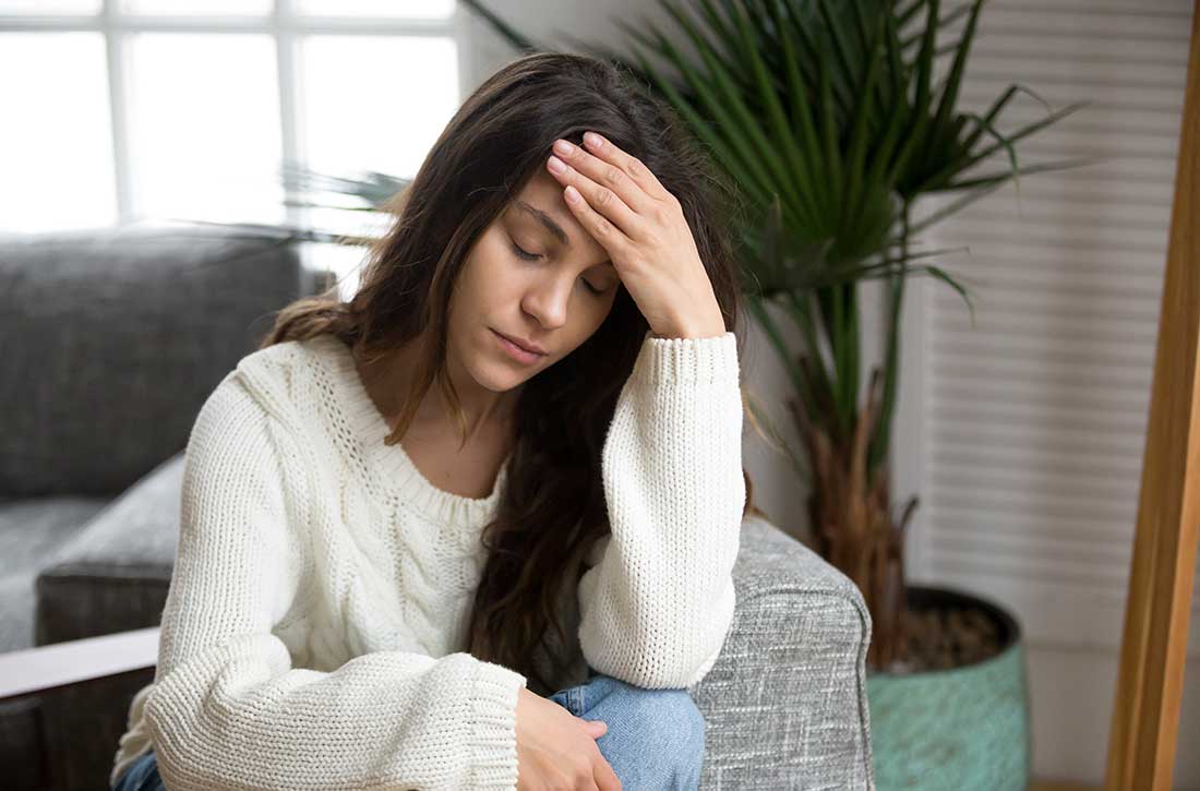 Woman looking down holding her head