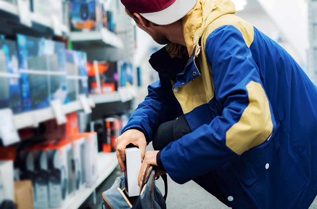 Man taking item off of shelf and putting into his backpack