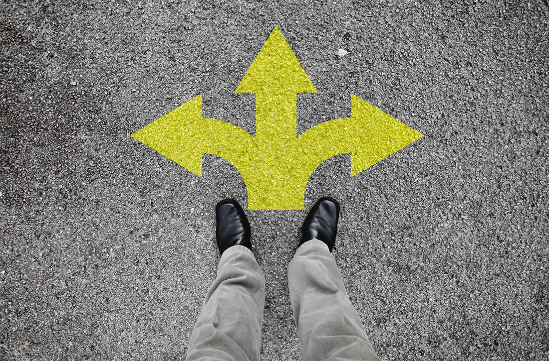 Standing on pavement in front of three arrows