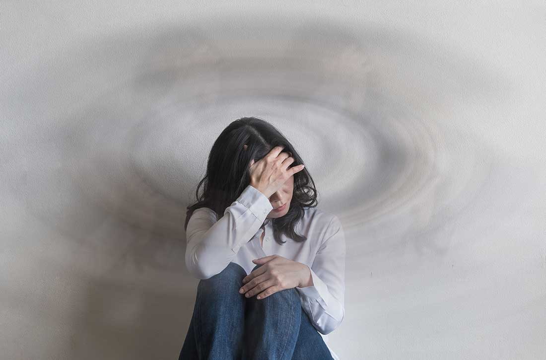 Woman sitting on floor holding her head