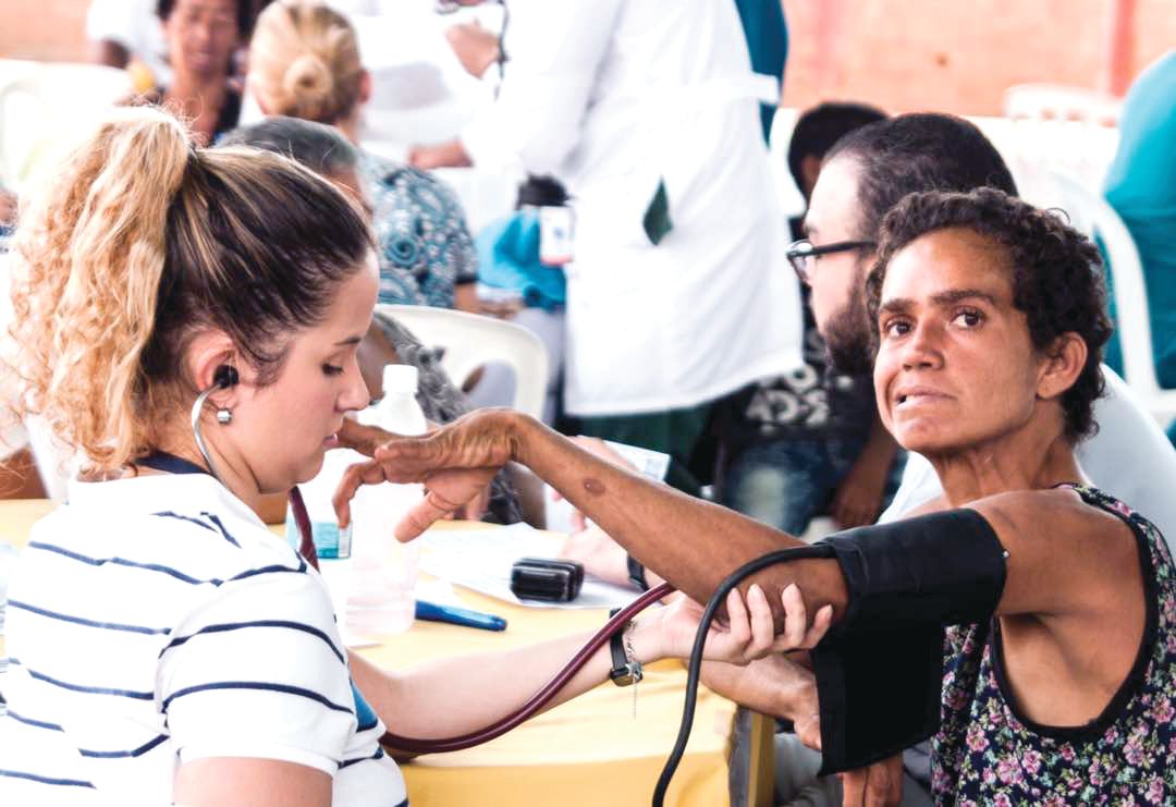 A health care worker takes vital signs from a patient during a medical visit in San Luis, Maracaibo, by the nongovernmental organization Primeros Auxilios LUZ.