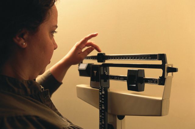 Woman standing on a doctor's scale, weighing herself