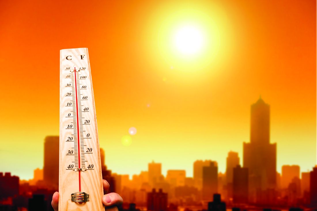 A person holding up a thermometer during a heat wave in the city.