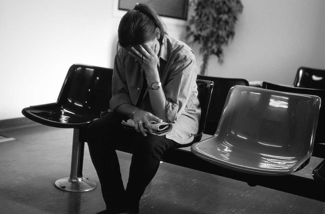 Woman holding her head sitting on chair