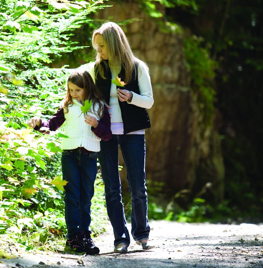 Mother and daughter walking on a road in the forest