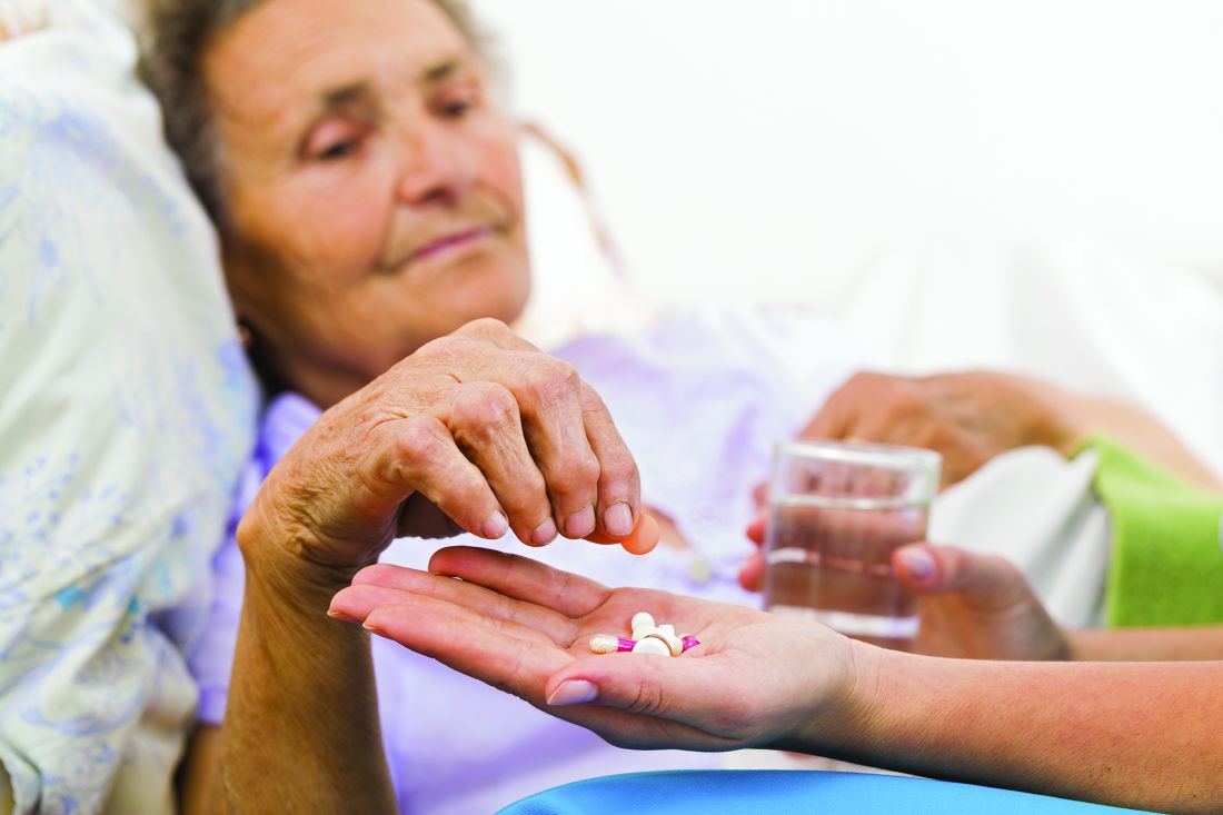 An older woman lying in bed takes medication.