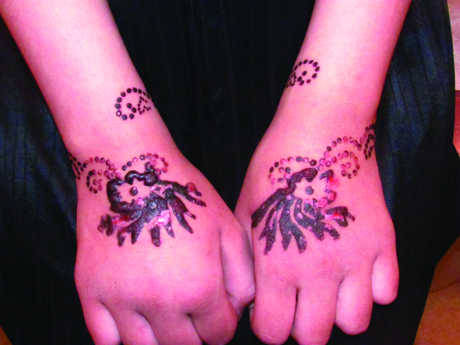 Red henna tattoo on the palmar surfaces of the hands.