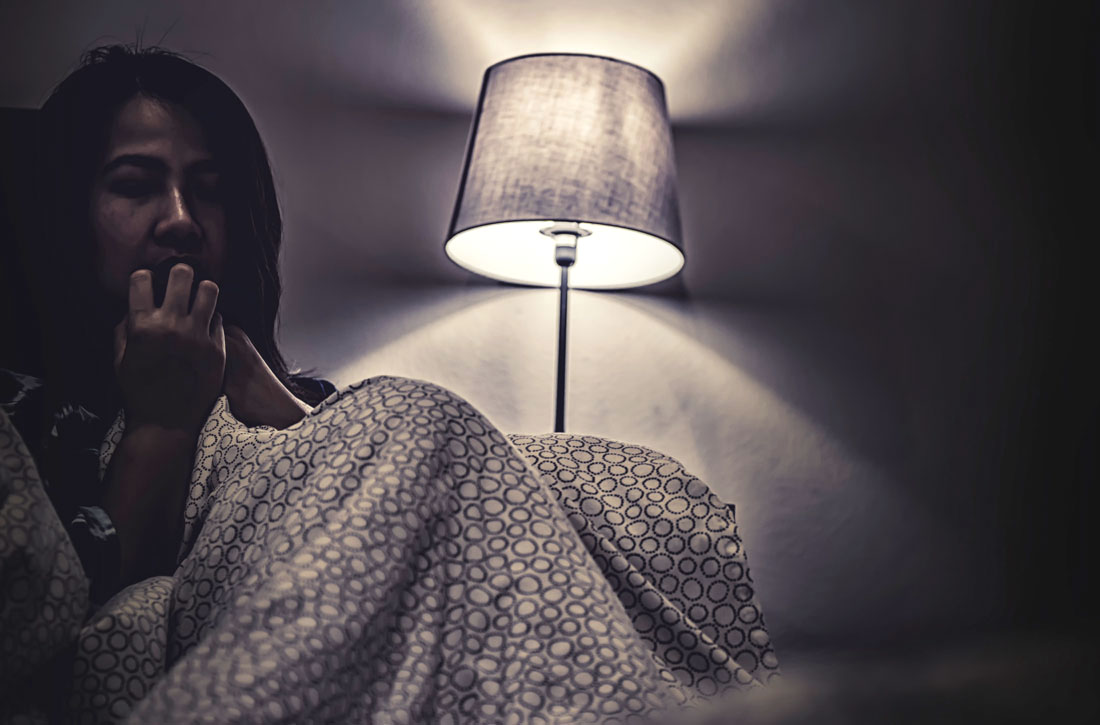 Woman sitting under blanket near lamp