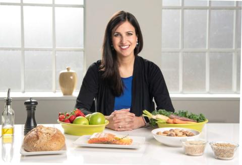 Dr. Mercedes Sotos Prieto sits at a table with an arrangement of nutritious foods.