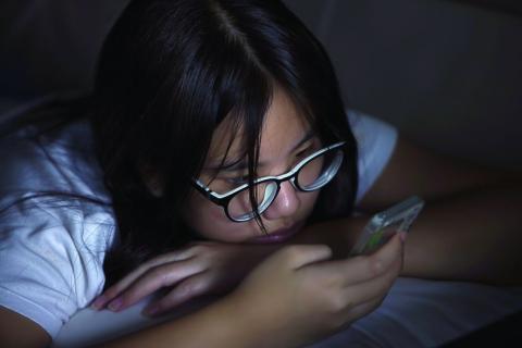 Teen in bed checking her cell phone