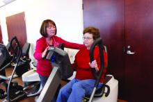 A patient does a rehab exercise under the supervision of a health care provider.