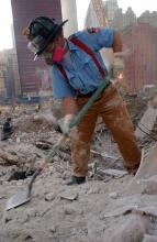 A New York firefighter digs through the rubble at Ground Zero while wearing a protective mask.