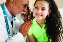 A doctor looks into the ear of a young girl