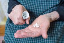 Elderly woman pouring pills into her hand.