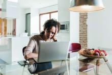 A woman sits at a table with a laptop computer