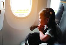 A young girl looks out the window of an airplane