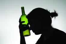 Silhouette of a woman holding a bottle to her forehead.