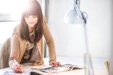 An individual works at a desk under a bright desk lamp.