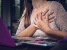 young woman cluching her heart with both hands at a desk