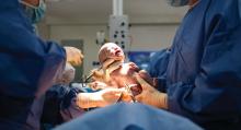 A baby who has just been delivered by C section is shown in an operating room