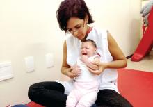 Baby with microcephaly undergoes a physical therapy session.