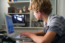 A teenager sits at his laptop