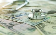 Paper money spread out under a stethoscope