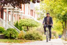 A man riding his bicycle on an urban sidewalk.