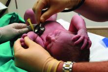 Doctor using stethoscope to listen to newborn's heart