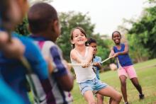 Children playing tug of war with rope in park