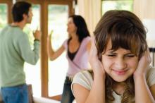 Girl covering her ears while parents fight