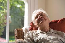 An elderly man sleeping in a chair.