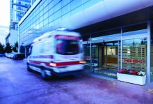 A blurry motion of an ambulance speeding by a hospital.