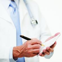 a partial photo of a doctor writing on a prescription pad