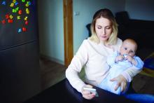 Young mother with baby sits and uses the phone.