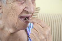 An elderly woman takes a pill.