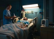 A patient in a hospital bed talks to a doctor