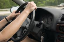 A person's arms and hands on a steering whell while driving