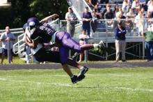 A high school football player tackles an opponent.