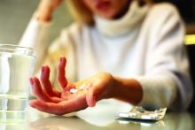 A woman holds opioid pills.