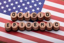 Opioid epidemic text on wooden cork over American flag.