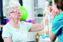 Doctor showing elderly woman model of spine