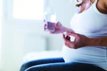 Pregnant woman taking large medication pill