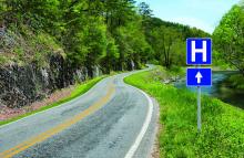 A rural road with a sign for a hospital is shown