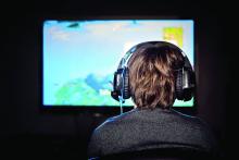 A young boy wearing a headset plays video game.