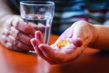 A hand holds vitamin D capsules