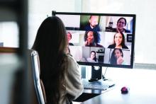 A woman video conferences with her coworkers from her office at home