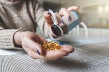 A woman empties a bottle of vitamin D pills into her hand.